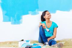 Jeune femme peignant un nouvel appartement rénové avec de la peinture.