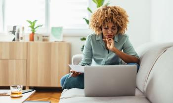 Jeune femme sur son canapé se renseigne son ordinateur pour bien choisir son syndic